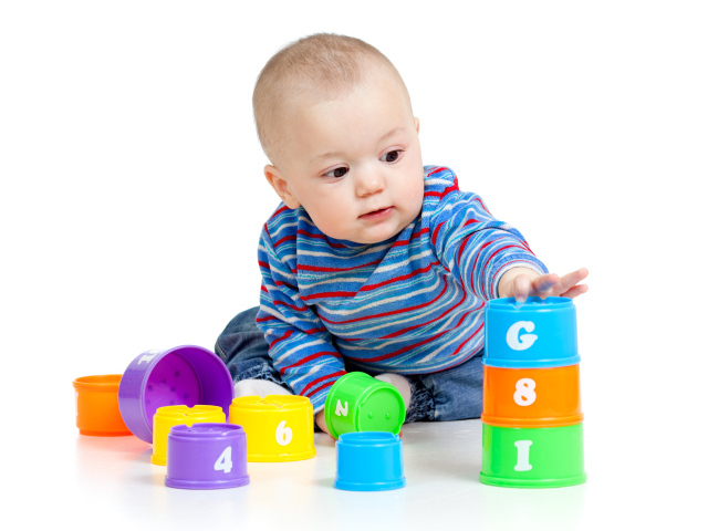 Маленький мальчик с разноцветными игрушками на белом фоне