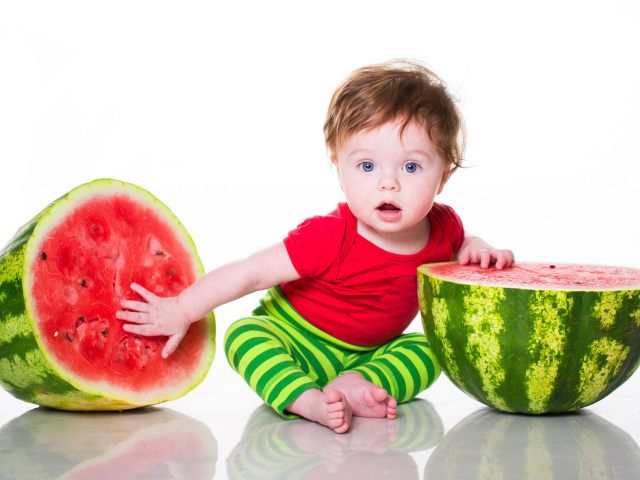 Маленький мальчик с половинами арбуза на белом фоне