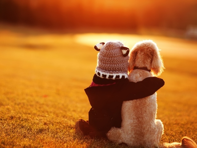 Маленький ребенок сидит с собакой на траве