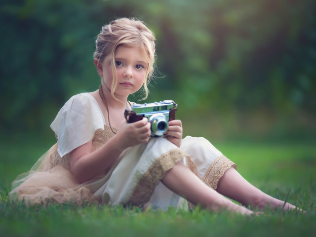 Маленькая русоволосая девочка с фотоаппаратом в руках