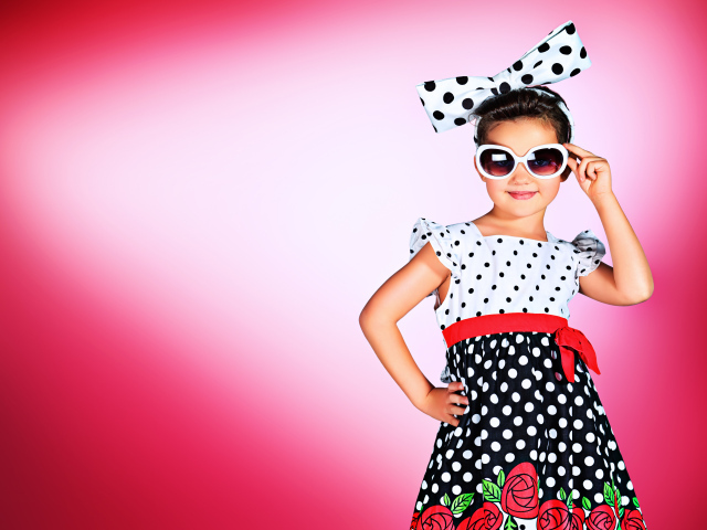 Маленькая девочка в красивом платье в горох на розовом фоне