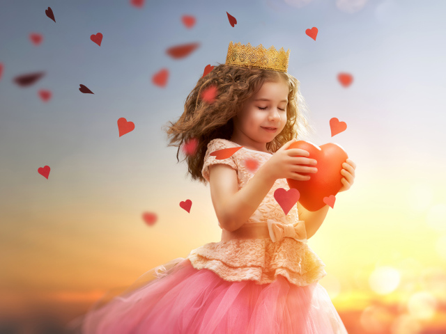 Маленькая девочка в костюме принцессы с красным сердцем в руках