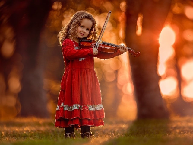 Маленькая девочка в красном платье со скрипкой в руках 