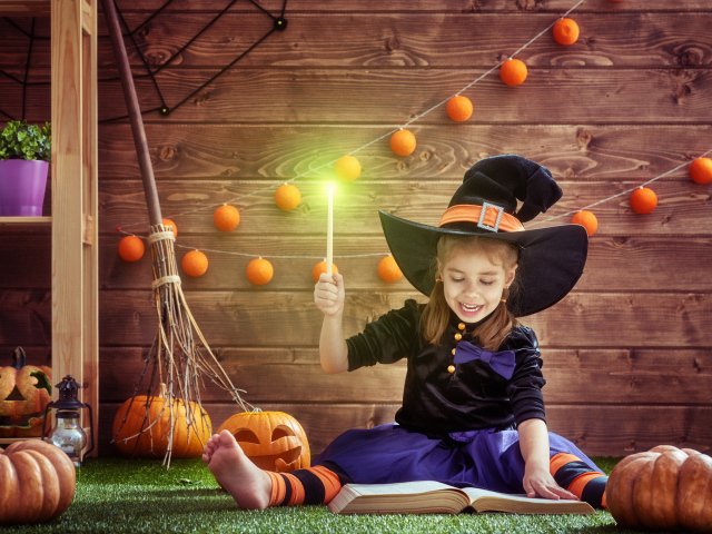 Маленькая девочка в костюме ведьмы с волшебной книгой на Хэллоуин