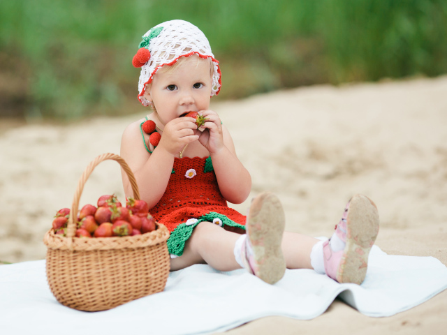 Маленькая девочка сидит с корзиной спелой клубники