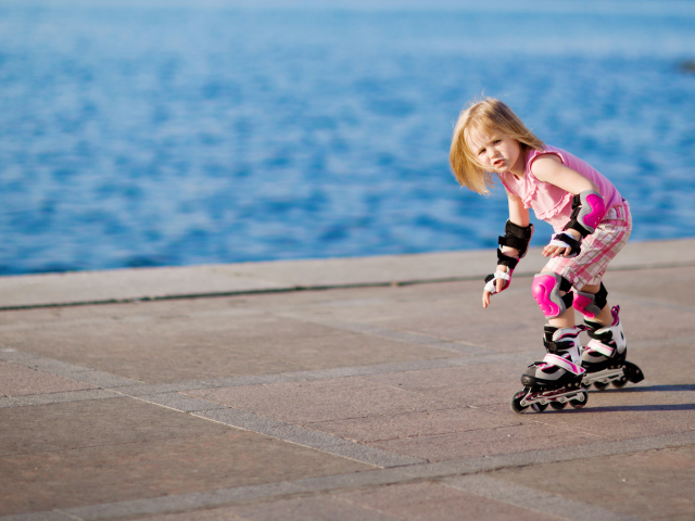 Маленькая девочка катается на роликах на побережье