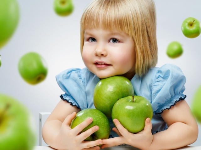 Маленькая девочка с зелеными яблоками в руках
