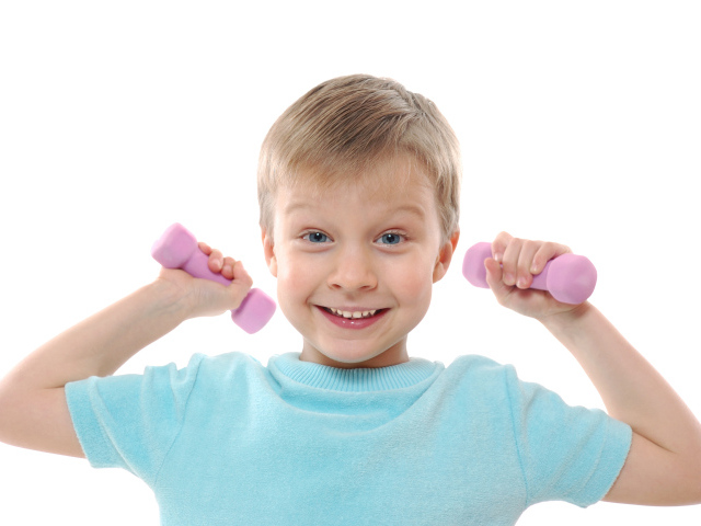 Маленький улыбающийся мальчик с гантелями на белом фоне