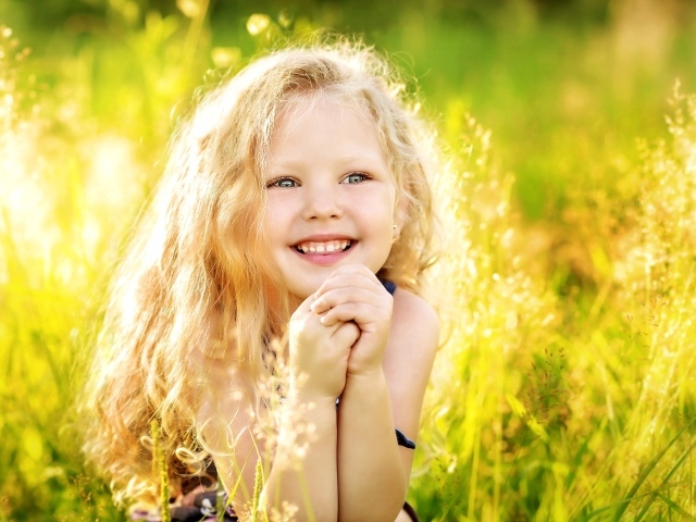 Маленькая улыбающаяся девочка в лучах солнца