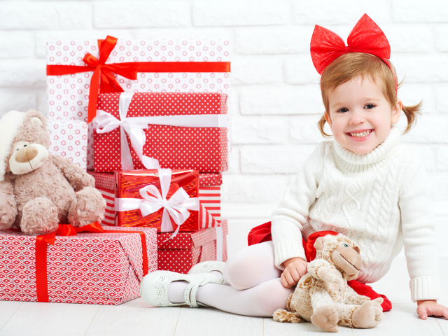 Маленькая улыбающаяся девочка с подарками на новый год