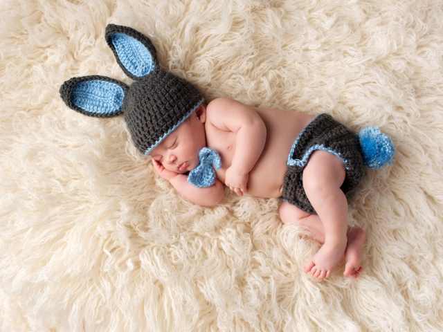 Спящий младенец в вязаном костюме зайца