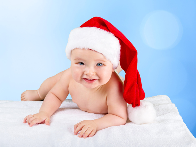 Улыбающийся грудной ребенок в новогодней шапке