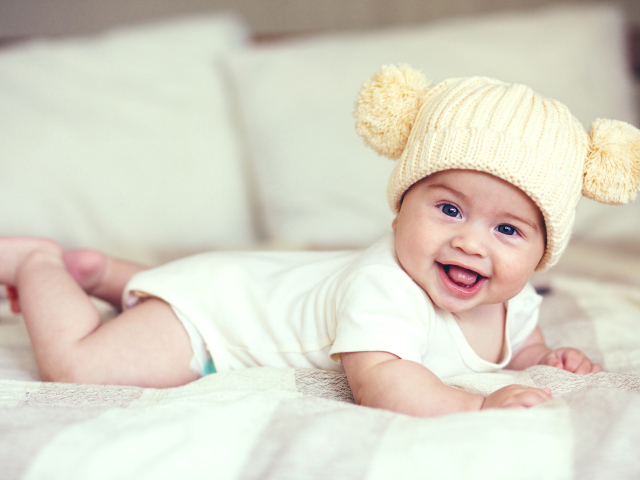 Улыбающийся грудной ребенок в забавной вязаной шапке