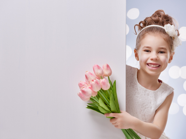 Улыбающаяся маленькая девочка с букетом розовых тюльпанов