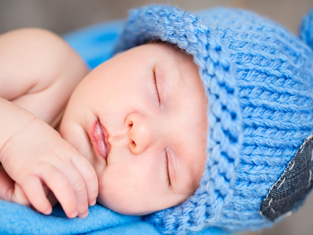 Милый спящий младенец с синей вязаной шапке