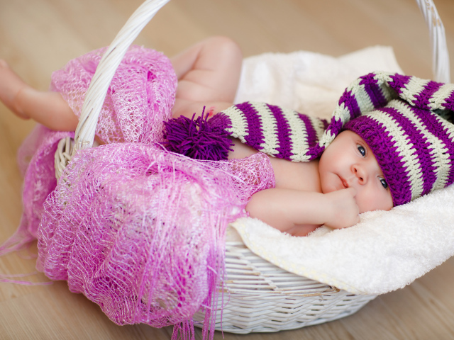 Младенец в красивой вязаной шапке лежит в корзине