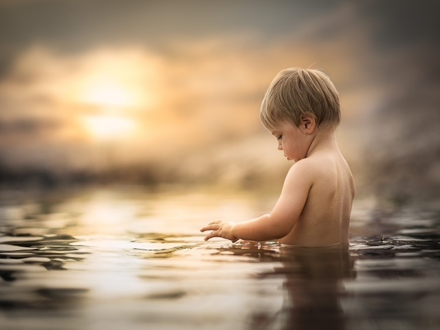 Маленький мальчик купается в воде 
