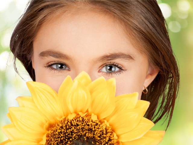 Взгляд маленькой девочки шатенки с подсолнухом в руках