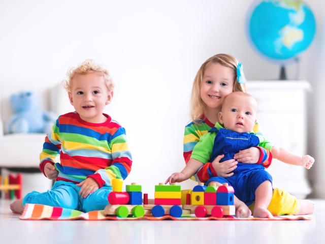 Три ребенка играют с игрушечным поездом