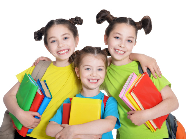 Три маленькие улыбающиеся девочки с книгами на белом фоне