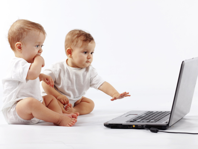 Два младенца перед ноутбуком на белом фоне