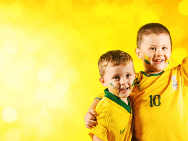 Два маленьких мальчика в спортивной форме на желтом фоне
