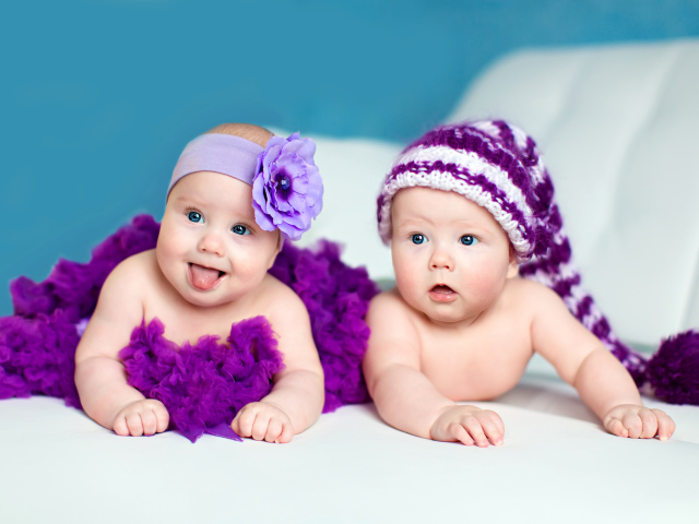 Два маленьких забавных младенца в красивых фиолетовых костюмах