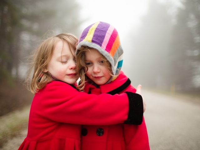 Две маленькие девочки обнимают друг друга 