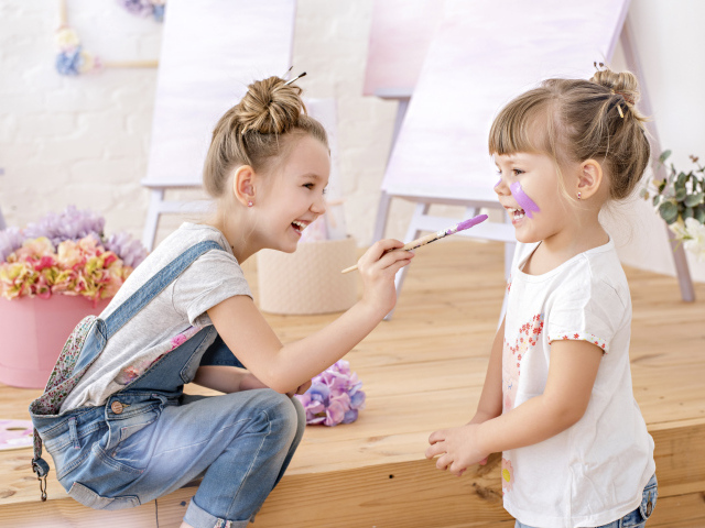 Две маленькие девочки играют с красками