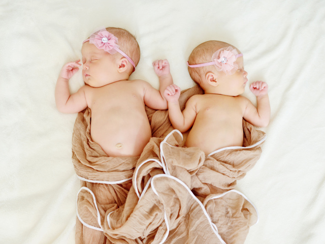 Два спящих младенца с розовыми цветами на голове