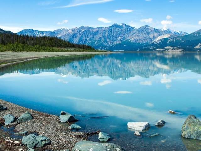 Горы отражаются в голубой воде озера Клуэйн, Национальный парк на территории Юкон, Канада.