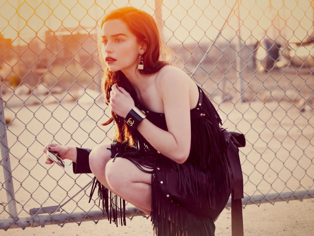 Актриса Эмилия Кларк в красивом черном платье в лучах солнца