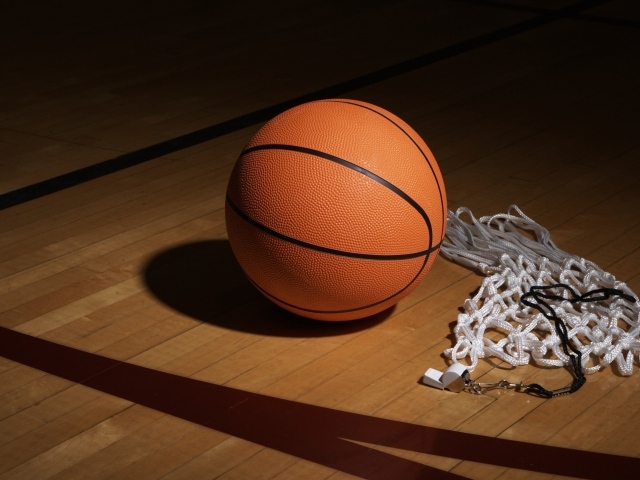 Баскетбольный мяч, свисток  и сетка на полу в спортзале 