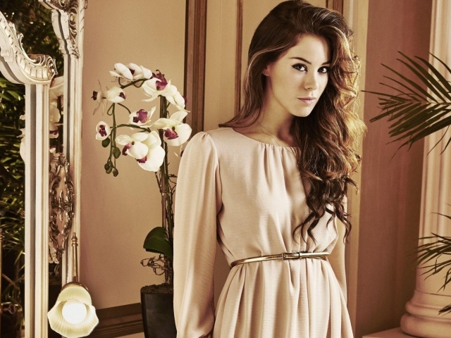 Брюнетка актриса Роксанна Макки стоит рядом с цветком орхидеи