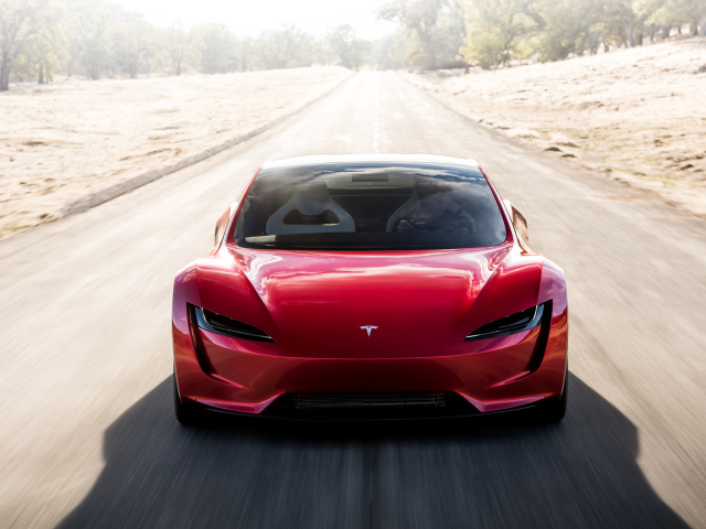 Красный автомобиль Tesla Roadster на трассе, вид спереди