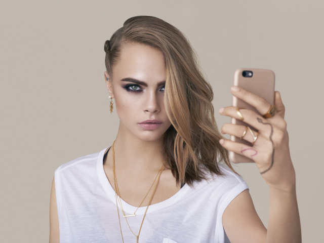 Молодая актриса Кара Делевинь с телефоном в руках