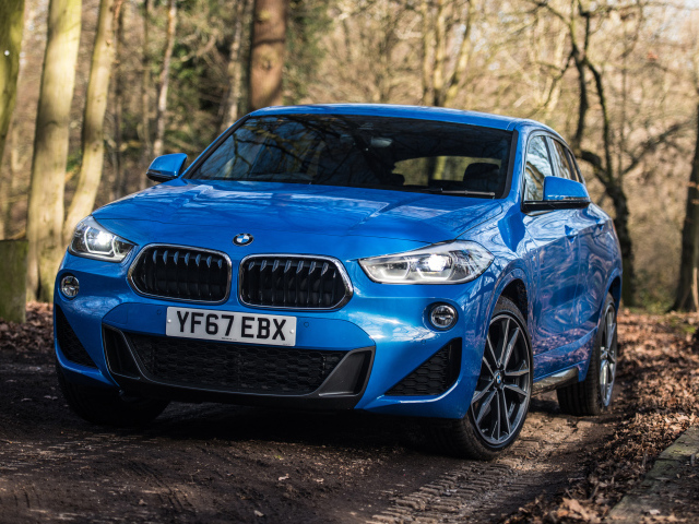 Синий автомобиль BMW X2 xDrive20d M Sport, 2018 на дороге в лесу
