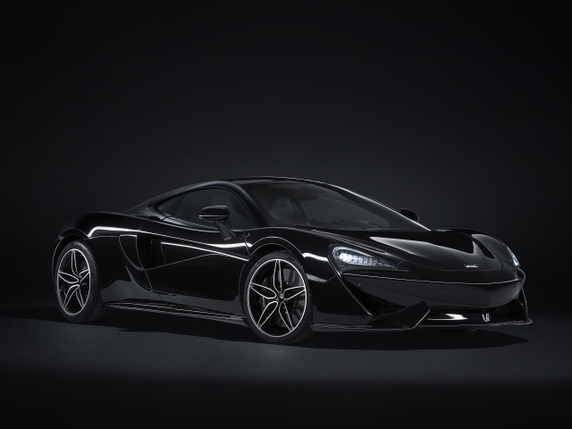 Черный спортивный автомобиль McLaren 570GT на сером фоне