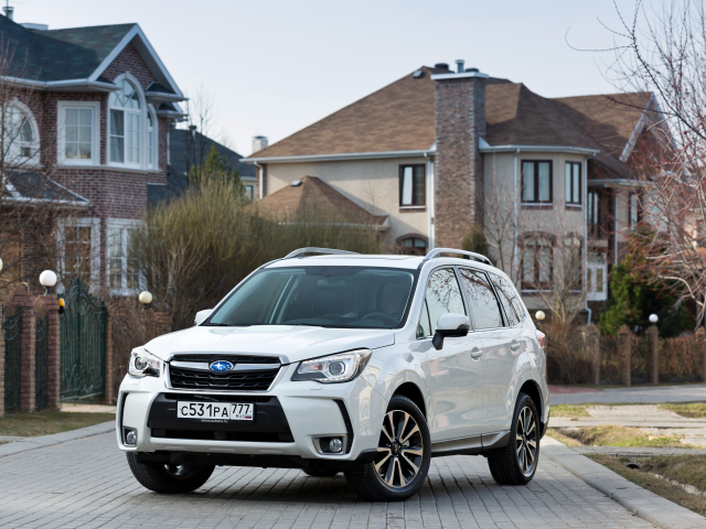 Белый автомобиль Subaru  Forester на улице у домов