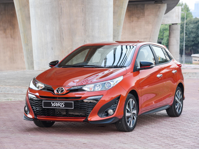 Красный автомобиль Toyota Yaris под мостом 