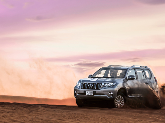 Серебристый внедорожник Toyota Land Cruiser Prado, 2018 едет по песку