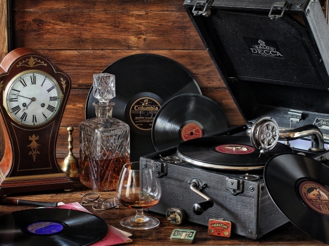Старый граммофон с виниловыми пластинками, часами и коньяком на столе