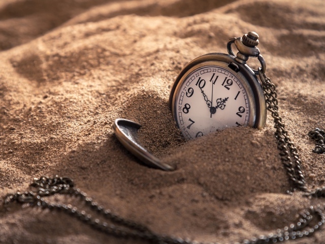 Карманные часы на цепочке в песке 