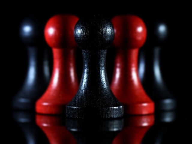 Красные и черные шахматные фигуры на черном фоне