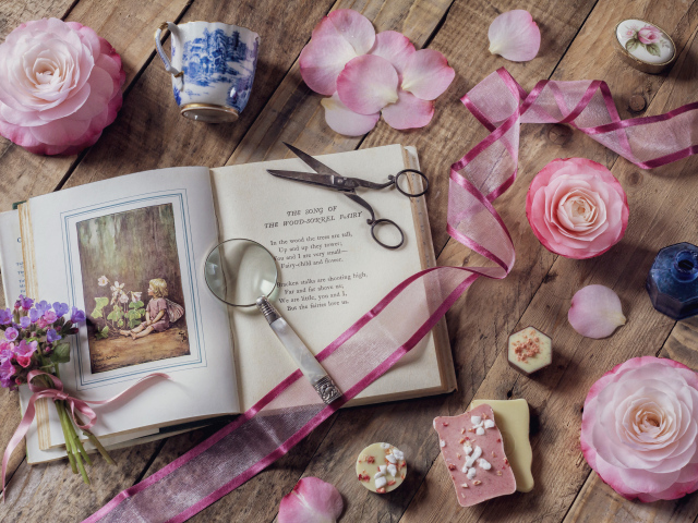 Старая книга на столе с увеличительным стеклом и искусственными цветами