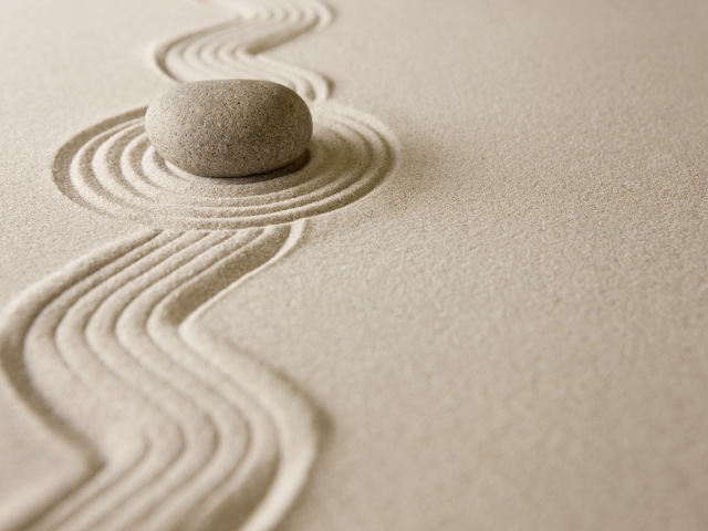 Камень лежит на рисунке на песке, дзен