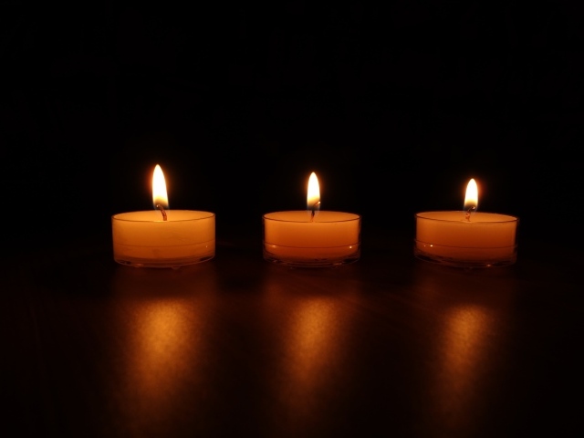 Три зажженные свечи на черном фоне