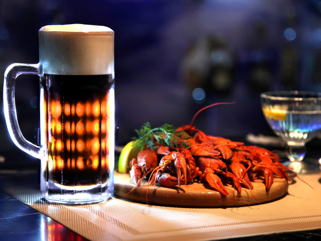 Бокал пива с вареными раками на столе