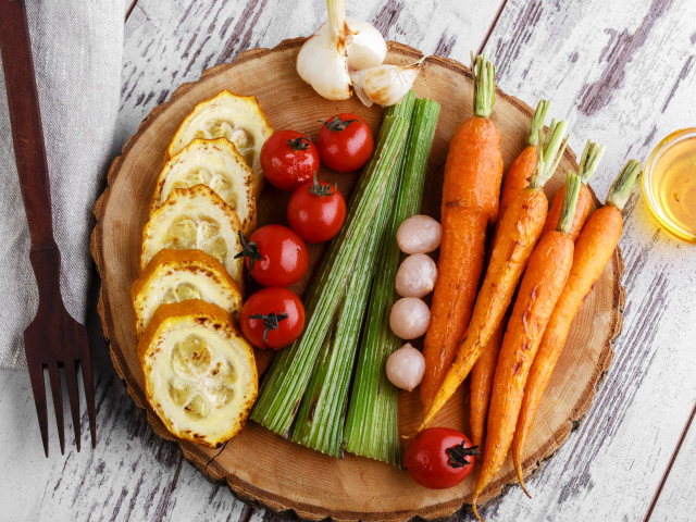 Печеные кабачки, помидоры, морковь, сельдерей и чеснок на разделочной доске