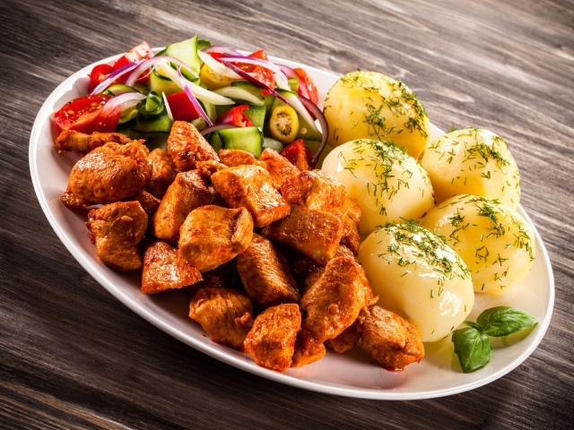 Вареный картофель с мясом и салатом на тарелке